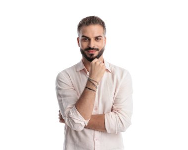 Düşünceli mutlu adam ileriye bakıyor, beyaz arka planda dururken çeneye dokunuyor ve hayal kuruyor.