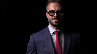 Güneş gözlüklü yakışıklı, olgun iş adamının, siyah arkaplan önünde mavi takım elbise giyip, ona göre ayarladığı bir proje videosu.