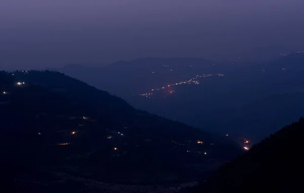 Горный пейзаж ночью с далекими лучами света — стоковое фото