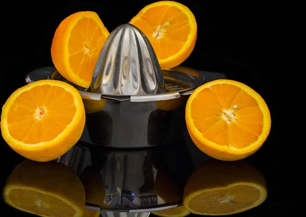 frontal close-up of manual citrus juicer with oranges in half with reflection and black background 2.jpg