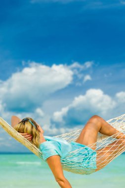 Kumsalda hamakta oturan şapkalı kadın. Seyahat ve tatil kavramı.
