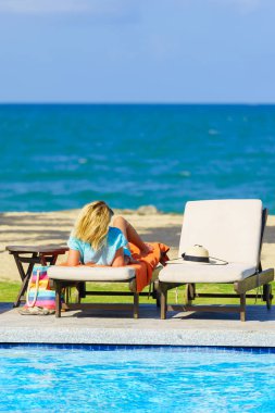 Bikini seksi kadın genç güzel kadın tatil yaz sezonunda şapka ile yan koltuğu kumsalda resort yüzme havuzu kenarında ile rahatlatıcı havuzu