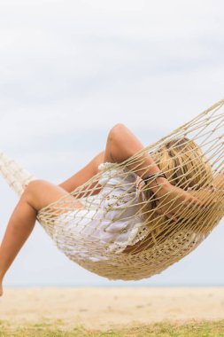 Hamak sahilde oturan kadın. Seyahat ve tatil kavramı.