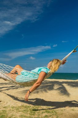Hamak sahilde oturan kadın. Seyahat ve tatil kavramı.