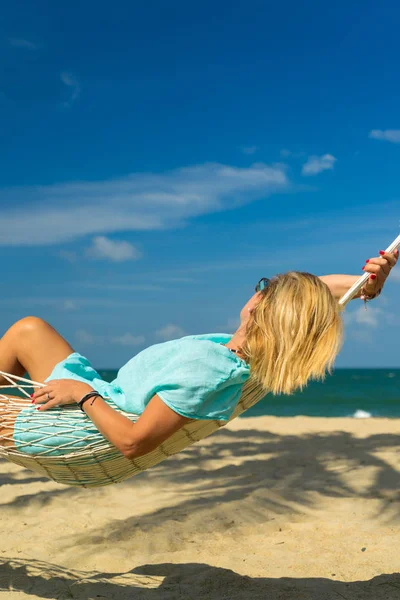 坐在沙滩上吊床里的妇女 旅行和度假概念 — 图库照片
