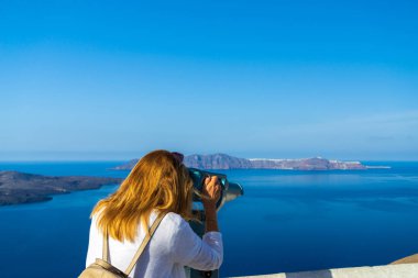 Yunanistan 'ın Santorini adasında manzaraya bakan lüks seyahat tatilcisi kadın. Deniz ve Caldera 'nın inanılmaz manzarası.