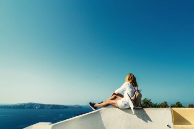 Yunanistan 'ın Santorini adasında manzaraya bakan lüks seyahat tatilcisi kadın. Deniz ve Caldera 'nın inanılmaz manzarası.