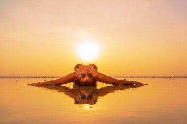 Gün batımında sahilde genç ve zinde bir kadının silueti. 