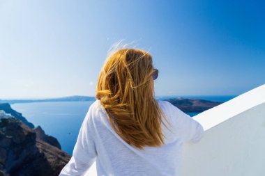 Yunanistan 'ın Santorini adasında manzaraya bakan lüks seyahat tatilcisi kadın. Deniz ve Caldera 'nın inanılmaz manzarası.