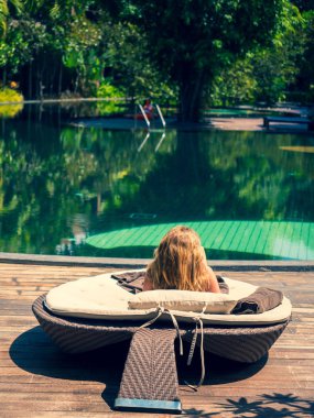 Tarafından havuz kenarında oturan ve turkuaz su havuzu, arıyorum güzel kadın lüks beach resort Bali, Endonezya yaz tatili harcama