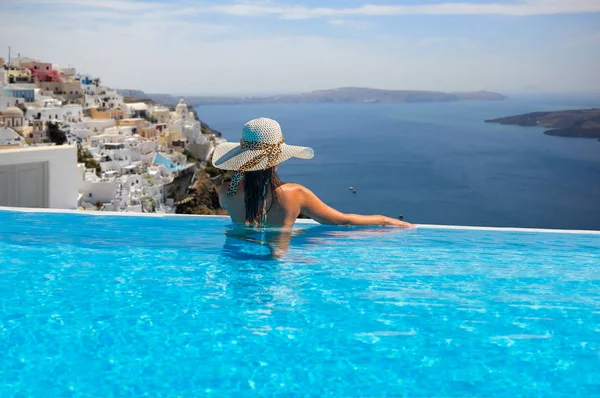 女性はプールでリラックスを楽しみ サントリーニ島ギリシャの景色を見て — ストック写真