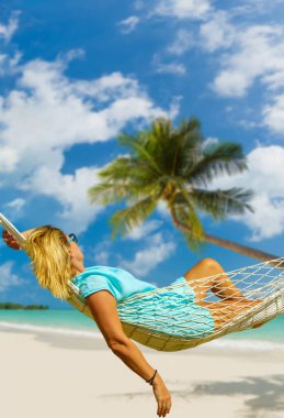 Hamak sahilde oturan kadın. Seyahat ve tatil kavramı.