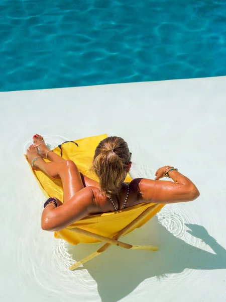 Kvinna sitter på en transat vid poolen — Stockfoto