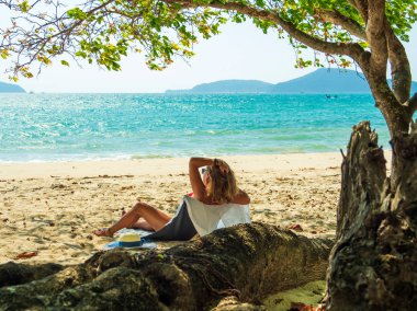 Bir kadın, tropikal plajda tatilin tadını çıkarıyor. 