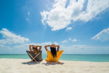 İki kadın tropikal sahilde tatilin tadını çıkarıyor. 