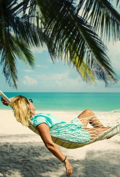 Vrouw zitten in een hangmat op het strand. — Stockfoto