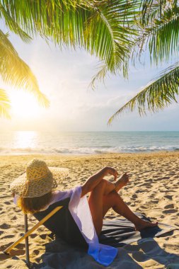 Bir kadın, tropikal plajda tatilin tadını çıkarıyor. 