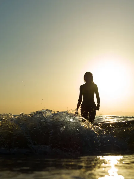 Mujer joven caminando en el mar al atardecer — Foto de Stock