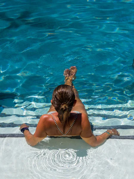 Woman relaxing in swimming pool at spa resort. r