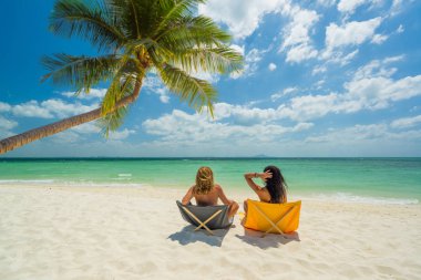 İki kadın tropikal sahilde tatilin tadını çıkarıyor. 