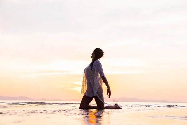 Vrouw op het strand bij zonsondergang — Stockfoto