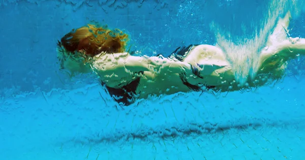 Vrouw onderwater in een glazen zwembad — Stockfoto