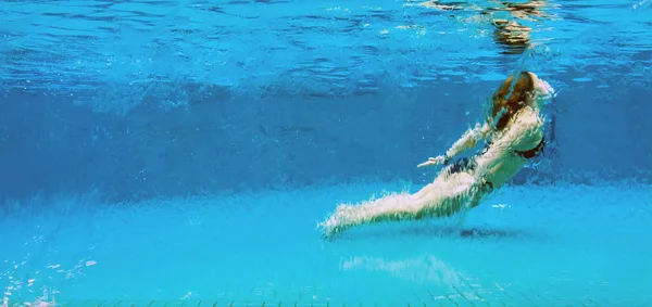 Frau unter Wasser im gläsernen Swimmingpool — Stockfoto