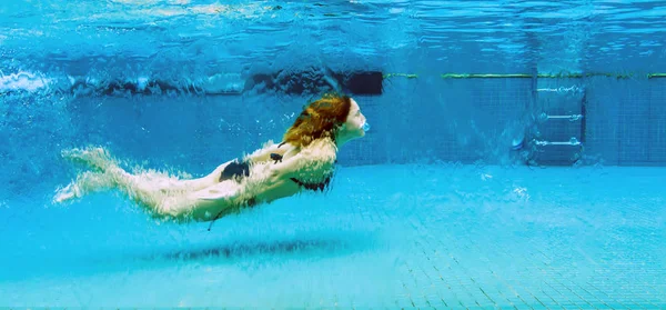 Женщина под водой в стеклянном бассейне — стоковое фото