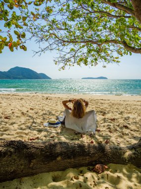 Bir kadın, tropikal plajda tatilin tadını çıkarıyor.
