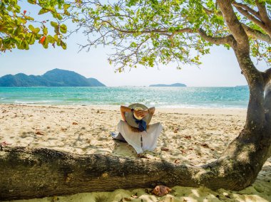 Bir kadın, tropikal plajda tatilin tadını çıkarıyor.