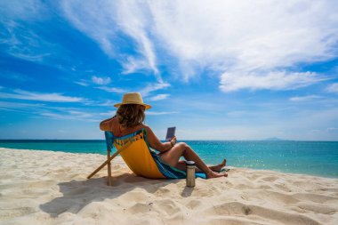 Bir kadın, tropikal plajda tatilin tadını çıkarıyor. 