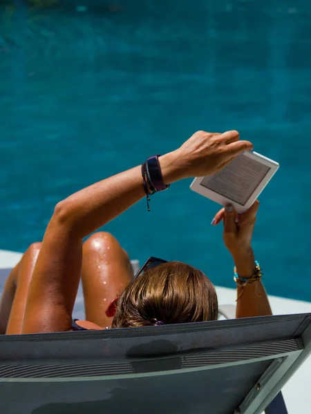 Woman at the swimming pool reading — Stock Photo, Image