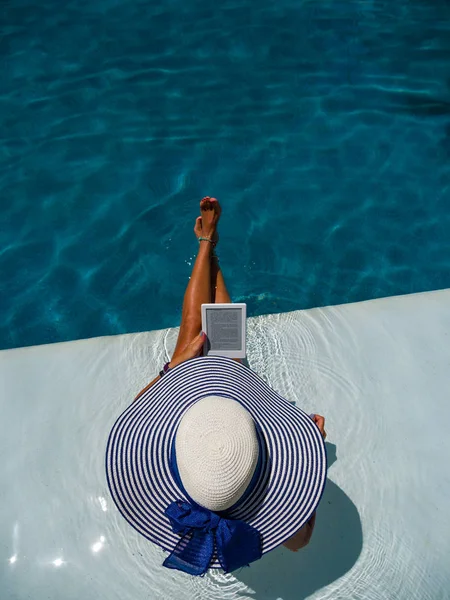 Woman at the swimming pool reading — Stock Photo, Image