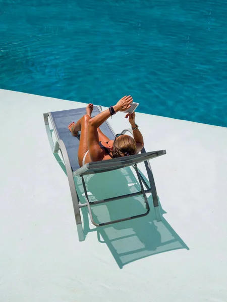 Frau im Schwimmbad liest Stockbild