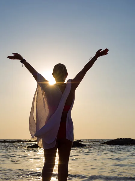 Jonge vrouw wandelen in de zee bij zonsondergang — Stockfoto