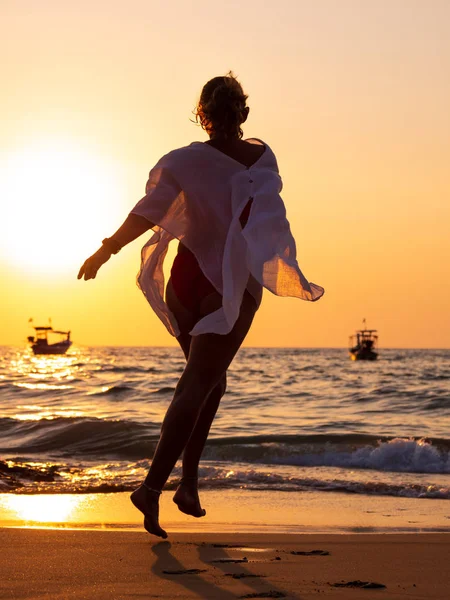 Gün batımında denizde yürüyen genç bir kadın. — Stok fotoğraf