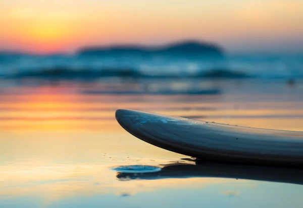 Prancha de surf na praia na costa do mar ao pôr-do-sol — Fotografia de Stock