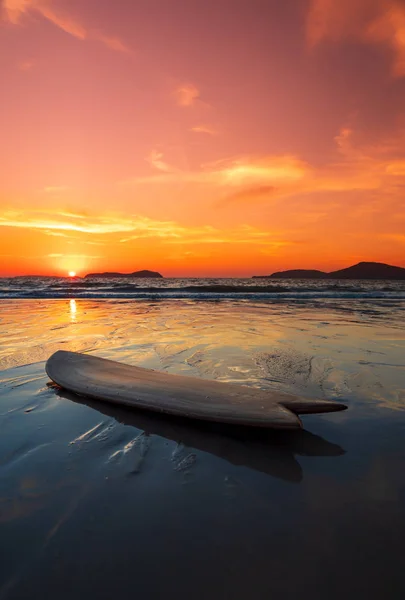 Planche de surf sur la plage au bord de la mer au coucher du soleil — Photo