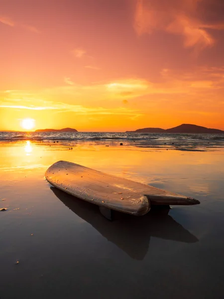 Prancha de surf na praia na costa do mar ao pôr-do-sol — Fotografia de Stock