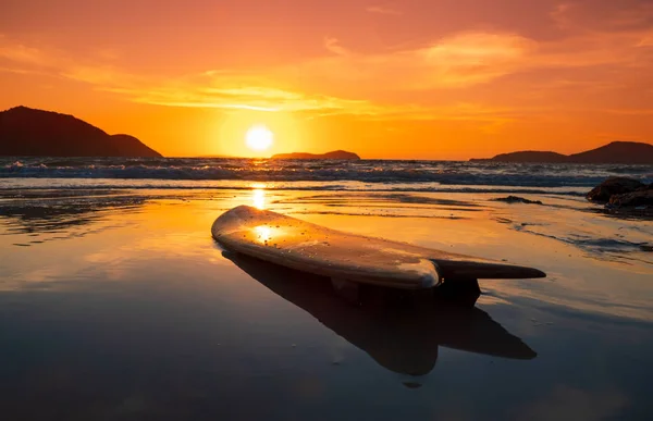 Tavola da surf sulla spiaggia in riva al mare al tramonto — Foto Stock