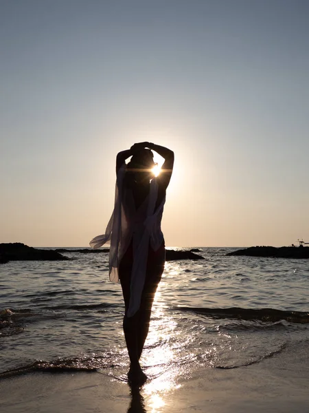 Młoda kobieta spacerująca w morzu o zachodzie słońca — Zdjęcie stockowe
