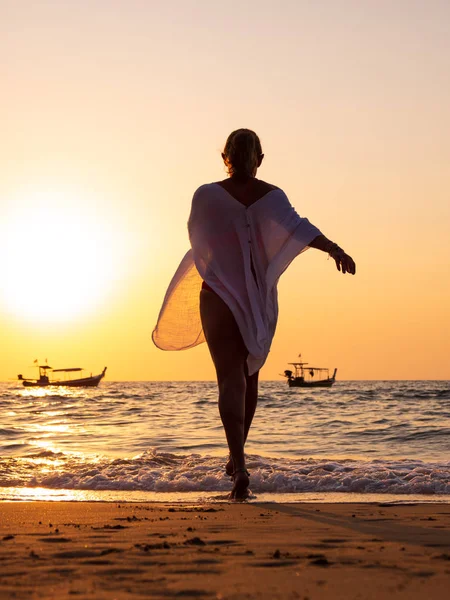 Jonge vrouw wandelen in de zee bij zonsondergang — Stockfoto