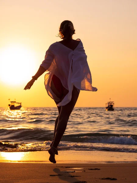 Νεαρή γυναίκα περπατά στη θάλασσα το ηλιοβασίλεμα — Φωτογραφία Αρχείου
