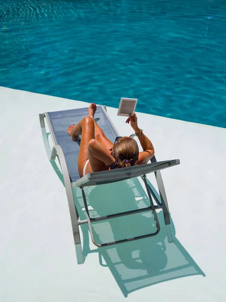 Woman at the swimming pool reading — Stock Photo, Image