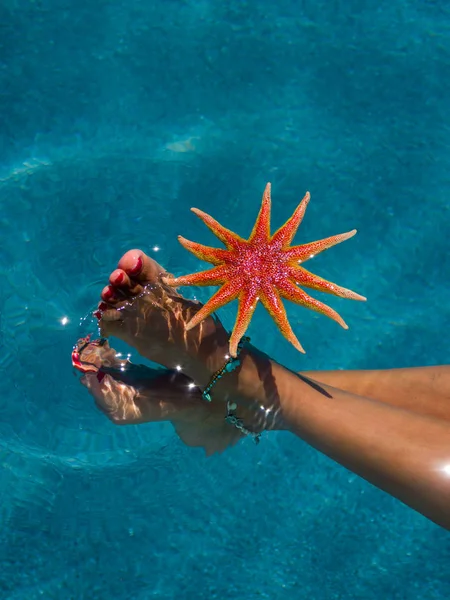 Patas de mujer con estrellas de mar en la piscina — Foto de Stock