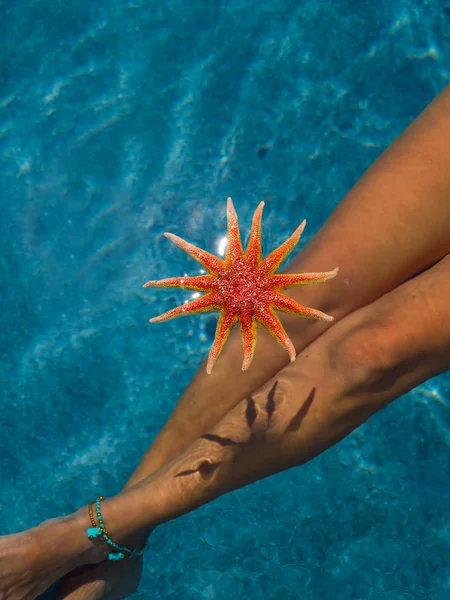 Woman's legs with starfish at the pool — Stock Photo, Image