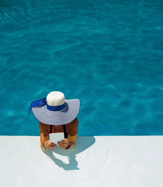 Mujer en la piscina leyendo — Foto de Stock