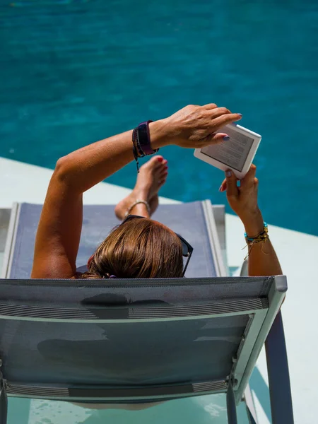 Woman at the swimming pool reading 스톡 사진