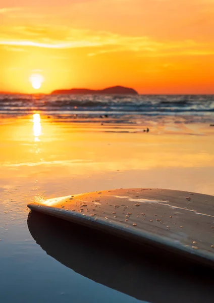 Planche de surf sur la plage au bord de la mer au coucher du soleil — Photo