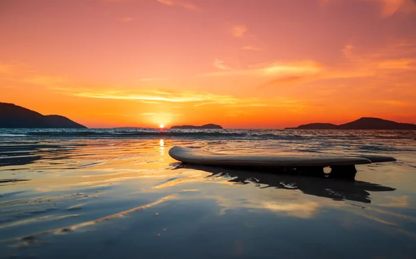 Planche de surf sur la plage au bord de la mer au coucher du soleil — Photo